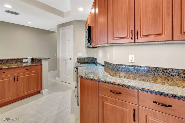 kitchen featuring light tile patterned floors, stainless steel electric range oven, and dark stone counters