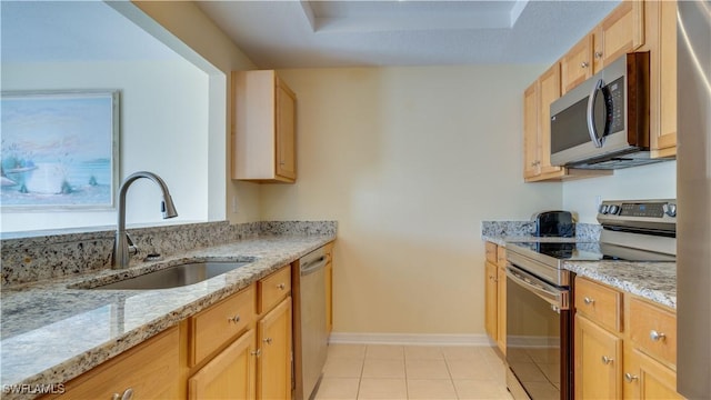 kitchen featuring sink, light tile patterned floors, appliances with stainless steel finishes, light stone countertops, and light brown cabinetry