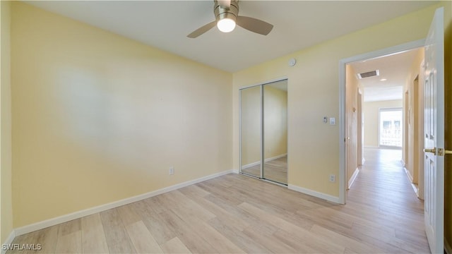 unfurnished bedroom with light hardwood / wood-style floors, ceiling fan, and a closet