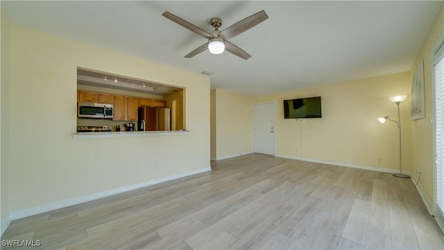 unfurnished living room featuring ceiling fan, a raised ceiling, and light hardwood / wood-style floors