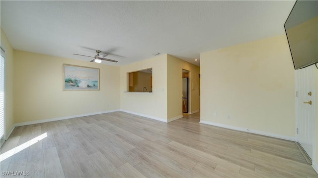 spare room with ceiling fan, a textured ceiling, and light wood-type flooring