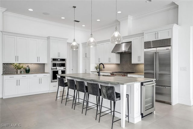 kitchen with pendant lighting, appliances with stainless steel finishes, white cabinetry, an island with sink, and sink