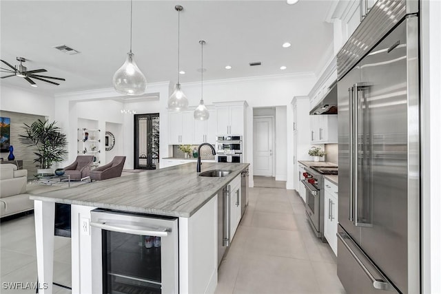 kitchen with premium appliances, a spacious island, white cabinetry, pendant lighting, and wine cooler