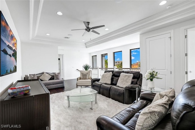 living room with hardwood / wood-style flooring, a raised ceiling, crown molding, and ceiling fan