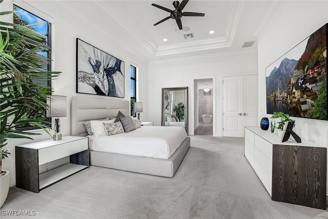 bedroom featuring ceiling fan, ensuite bathroom, a raised ceiling, and light carpet