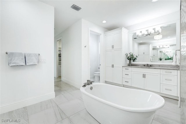 bathroom with toilet, vanity, and a tub to relax in