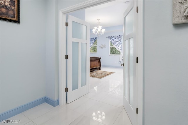 corridor featuring light tile patterned floors and an inviting chandelier