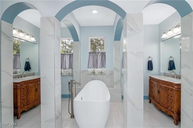 bathroom featuring a tub to relax in, tile walls, and vanity