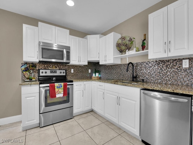 kitchen featuring stainless steel appliances, white cabinetry, sink, and dark stone countertops