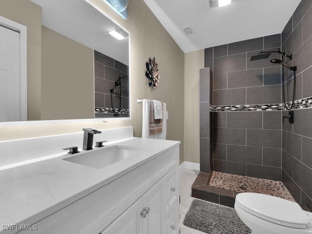 bathroom with vanity, tile patterned floors, toilet, and a tile shower