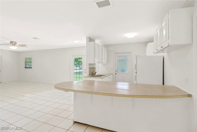 kitchen with sink, white cabinets, a kitchen bar, white fridge, and kitchen peninsula