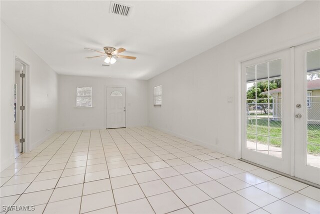 tiled spare room featuring ceiling fan and french doors