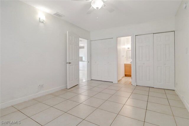 unfurnished bedroom with light tile patterned flooring, ceiling fan, and ensuite bath