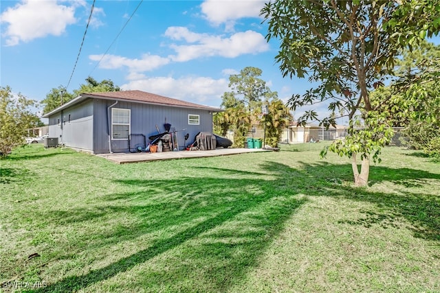 rear view of property featuring cooling unit and a lawn