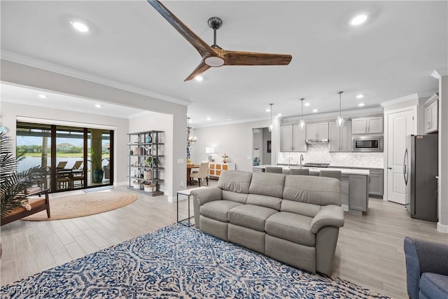 living room with ceiling fan, ornamental molding, and light wood-type flooring