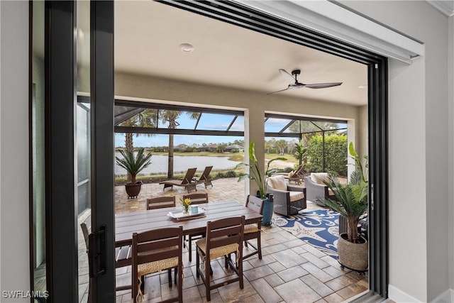 dining space with ceiling fan and a water view