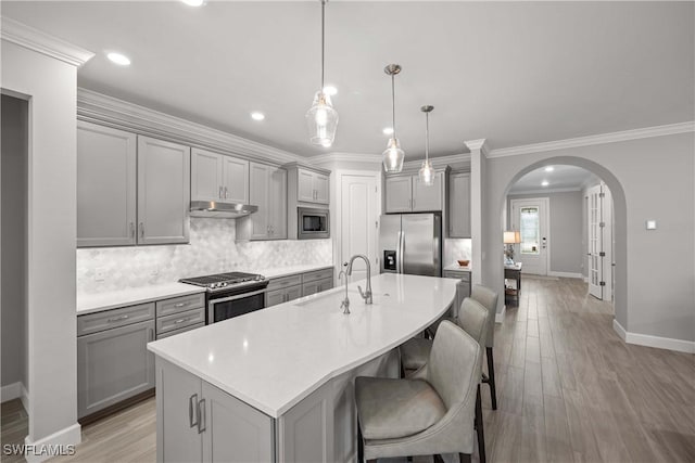 kitchen featuring appliances with stainless steel finishes, decorative light fixtures, sink, gray cabinetry, and a center island with sink