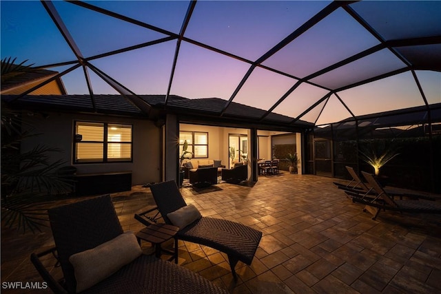 patio terrace at dusk with an outdoor living space and glass enclosure