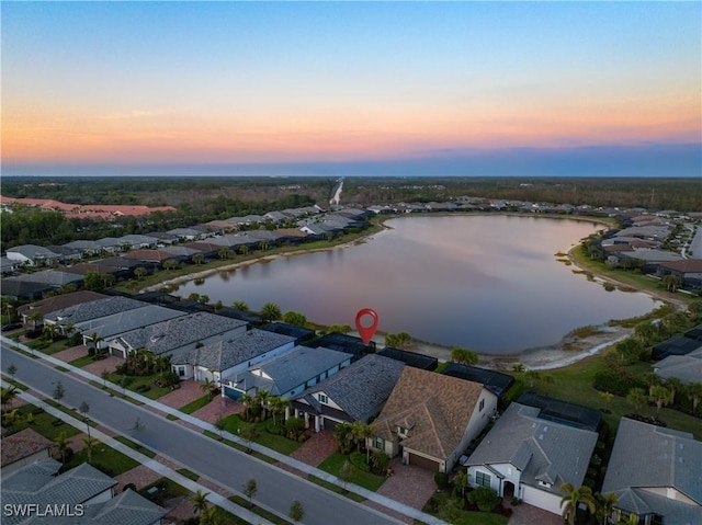 aerial view at dusk featuring a water view