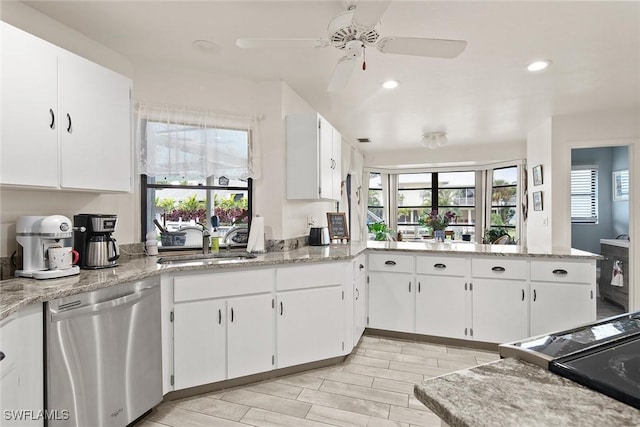 kitchen featuring light stone counters, dishwasher, sink, and white cabinets