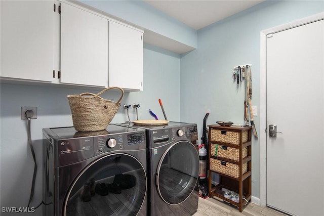 clothes washing area featuring cabinets and washing machine and clothes dryer