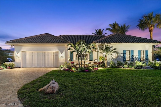 mediterranean / spanish-style home with a garage and a lawn