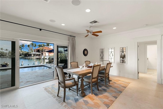 tiled dining area featuring a water view, ceiling fan, and crown molding