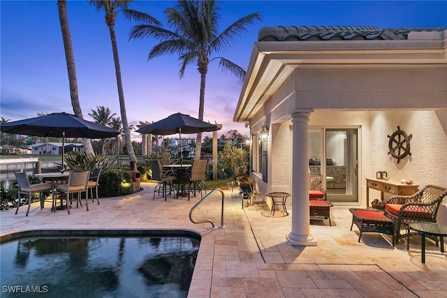 pool at dusk featuring a patio area