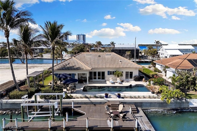 back of property with a water view and a patio area