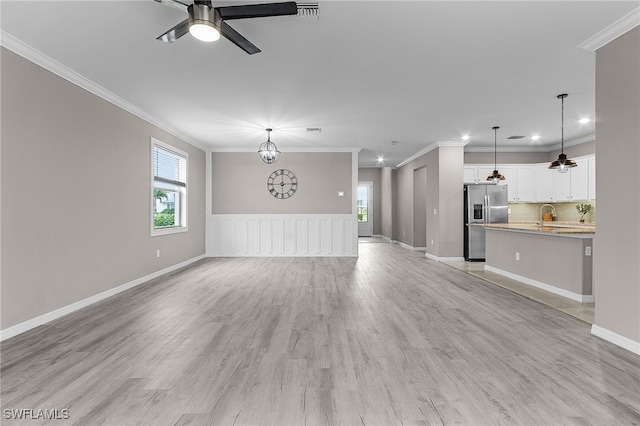 unfurnished living room with ceiling fan, sink, light hardwood / wood-style flooring, and ornamental molding