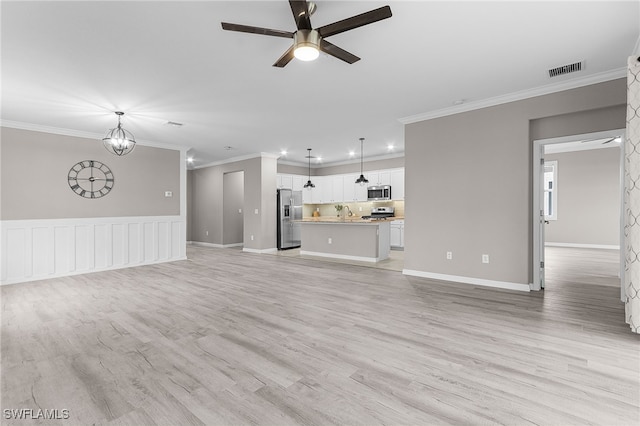 unfurnished living room with light wood-type flooring, ceiling fan with notable chandelier, ornamental molding, and sink