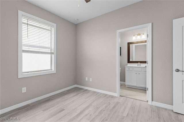 unfurnished bedroom featuring ceiling fan, sink, connected bathroom, and light wood-type flooring