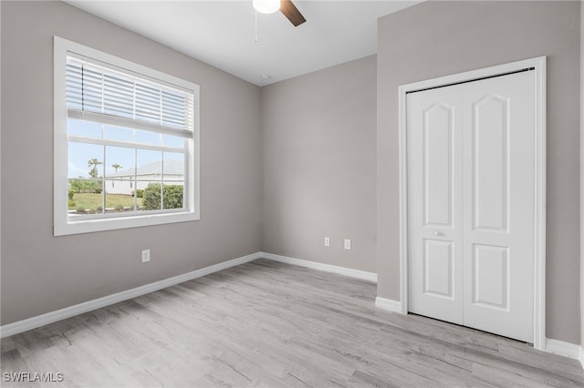 unfurnished bedroom with light hardwood / wood-style flooring, a closet, and ceiling fan