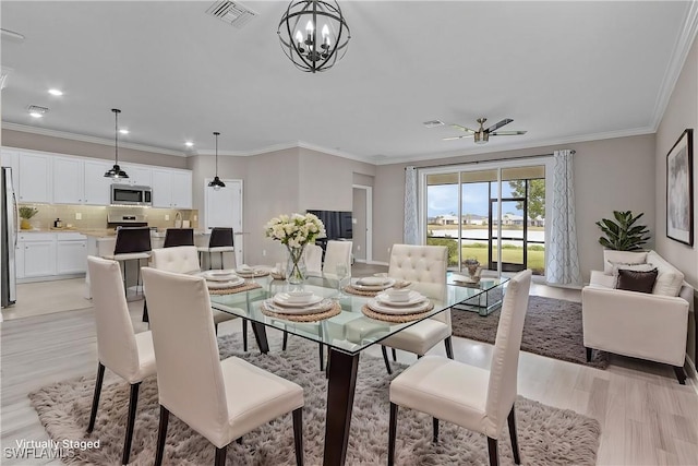 dining space featuring ceiling fan with notable chandelier, light hardwood / wood-style flooring, and ornamental molding