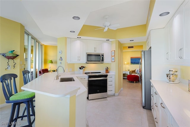 kitchen featuring sink, a breakfast bar area, white cabinetry, kitchen peninsula, and stainless steel appliances