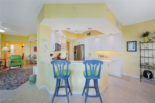 kitchen with a breakfast bar, white cabinetry, ceiling fan, kitchen peninsula, and stainless steel appliances