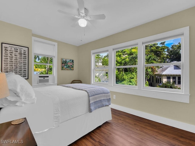 bedroom featuring dark hardwood / wood-style flooring, cooling unit, and ceiling fan