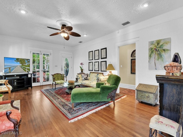 living room with hardwood / wood-style flooring, ceiling fan, a textured ceiling, and french doors