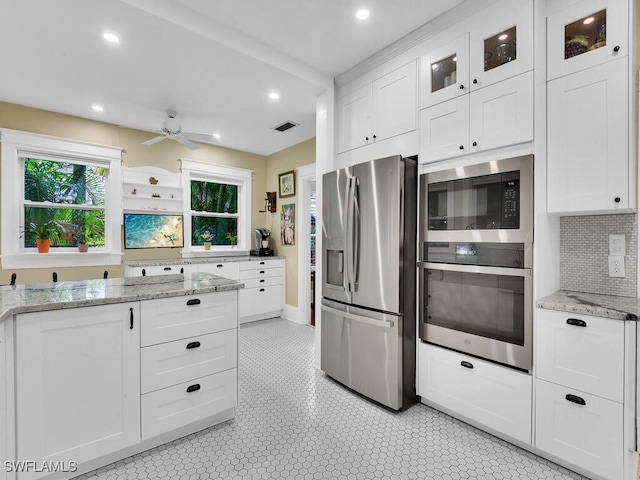 kitchen with white cabinetry, appliances with stainless steel finishes, light stone counters, and decorative backsplash