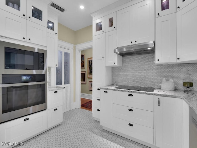 kitchen with light tile patterned floors, white cabinetry, light stone counters, black appliances, and decorative backsplash