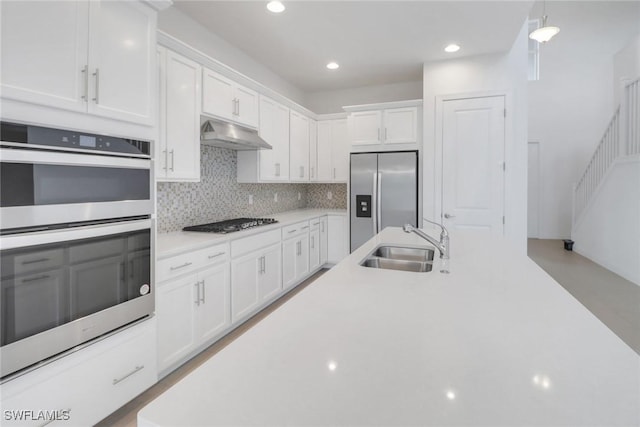 kitchen featuring stainless steel appliances, sink, white cabinets, and decorative light fixtures