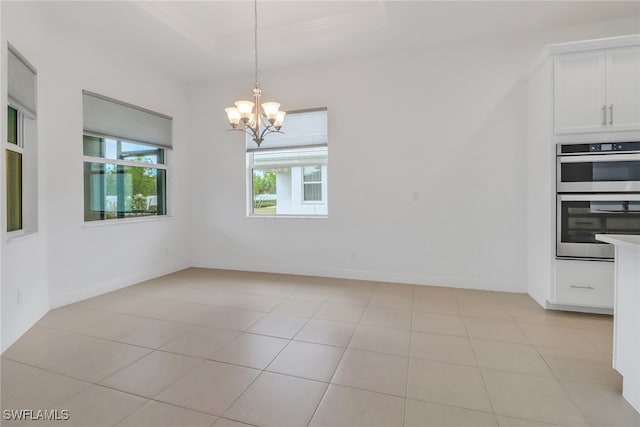 unfurnished dining area featuring an inviting chandelier, light tile patterned floors, and a tray ceiling
