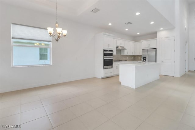 kitchen with white cabinetry, decorative light fixtures, a center island with sink, stainless steel appliances, and decorative backsplash