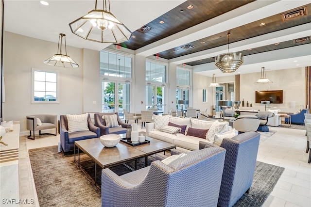 tiled living room with plenty of natural light, a chandelier, and a high ceiling