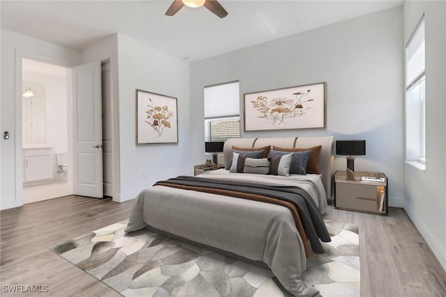 bedroom with connected bathroom, multiple windows, and light wood-type flooring