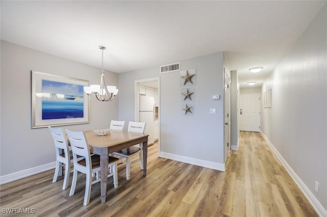 dining area featuring light hardwood / wood-style flooring and a chandelier