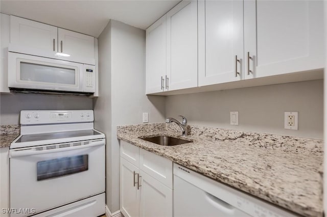 kitchen with white cabinetry, white appliances, light stone countertops, and sink