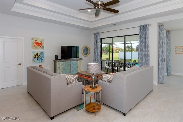 living room with ceiling fan, a tray ceiling, and crown molding