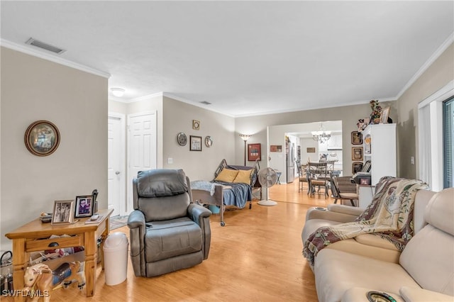 living room with crown molding, light wood-type flooring, and an inviting chandelier