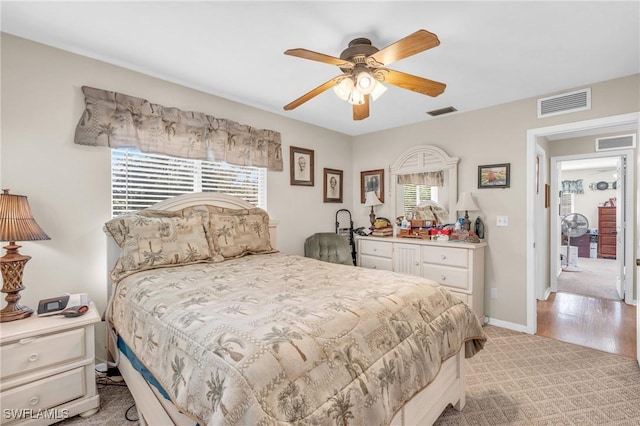 bedroom with ceiling fan, light colored carpet, and multiple windows